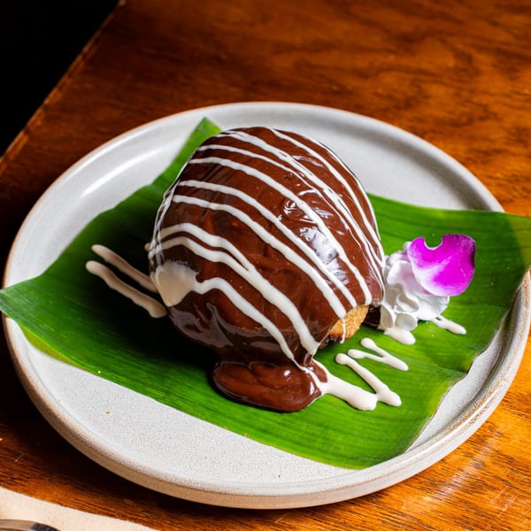 Nur Thai's fried ice cream, drizzled with chocolate and white sauce, garnished with a purple orchid.