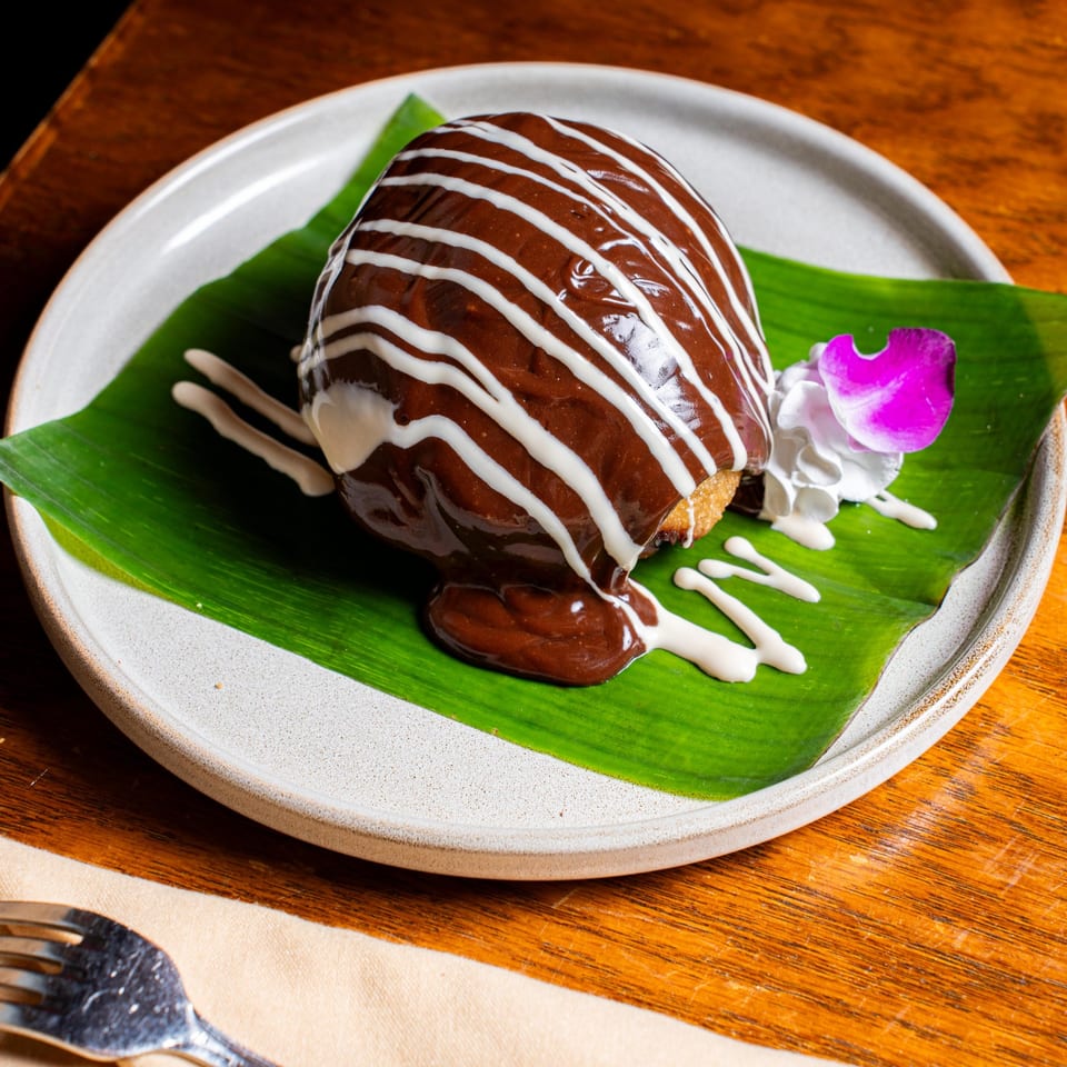 Nur Thai's fried ice cream dessert, drizzled with chocolate and white sauce, garnished with an orchid.