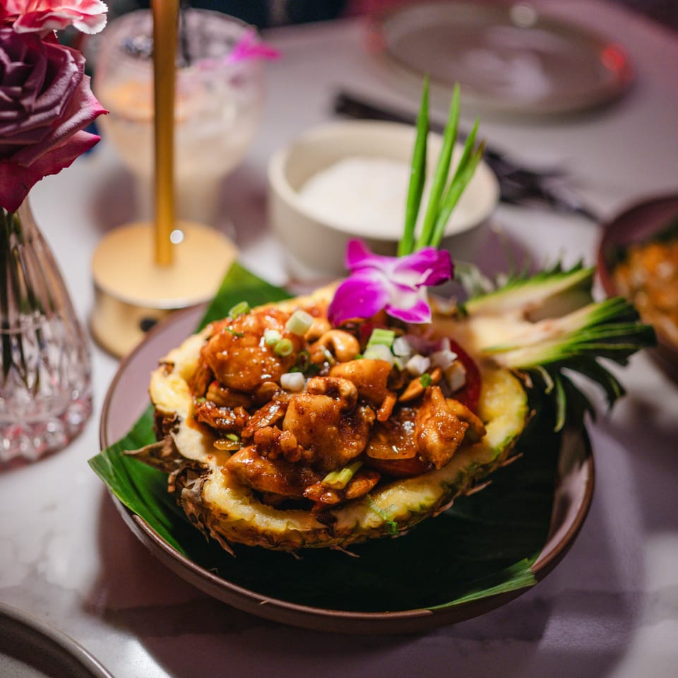 Nur Thai's pineapple fried rice, garnished with cashews, green onions, and an orchid.